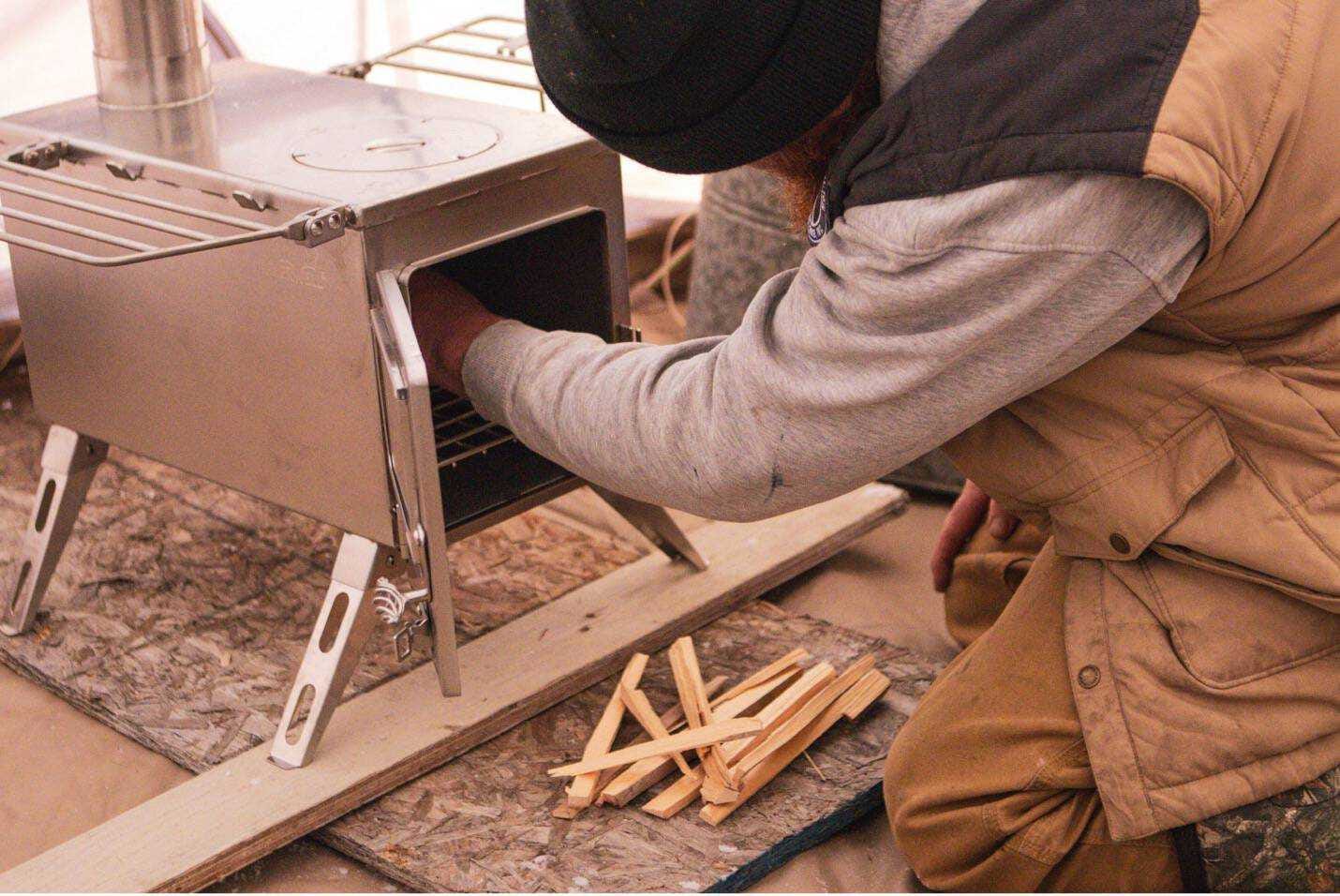 Loading kindling wood in a tent stove Loading kindling wood in a tent stove