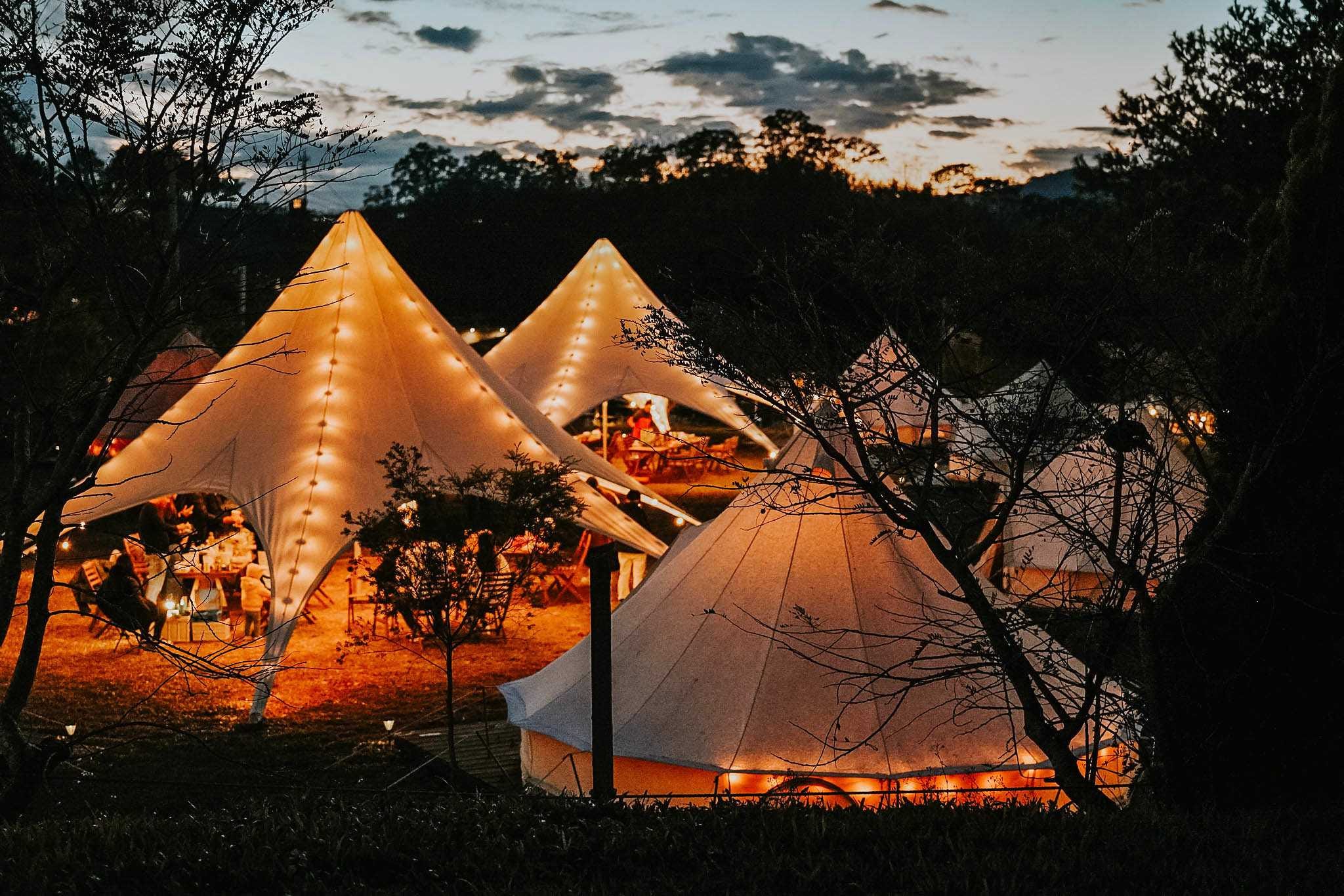 mutliple canvas tents glowing at dusk mutliple canvas tents glowing at dusk