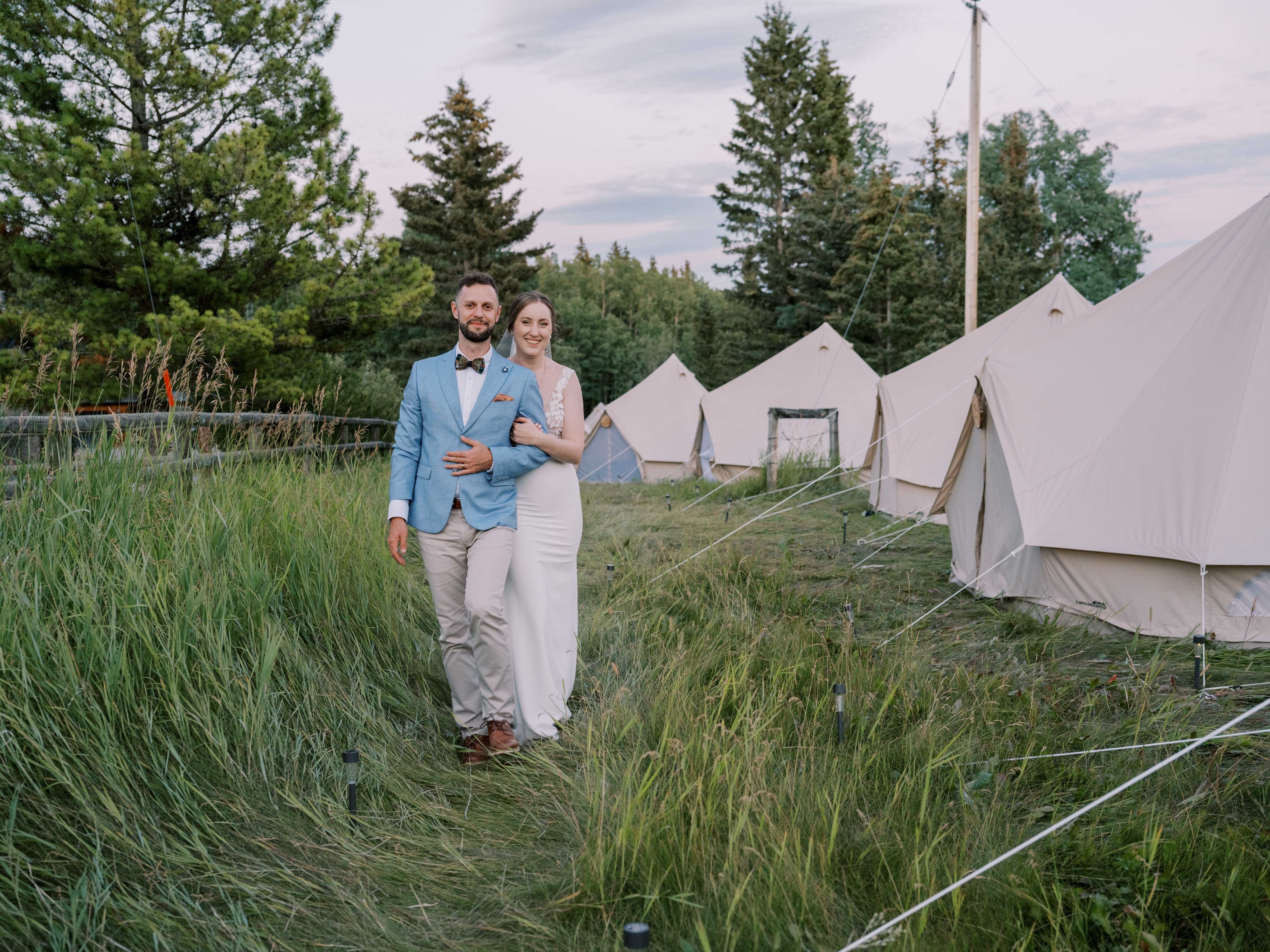 happy couple in grasslands with multiple sibley canvas tents happy couple in grasslands with multiple sibley canvas tents