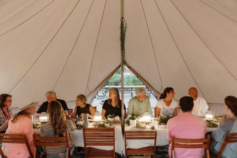 People dinning at a large table inside a sibley canvas tent People dinning at a large table inside a sibley canvas tent
