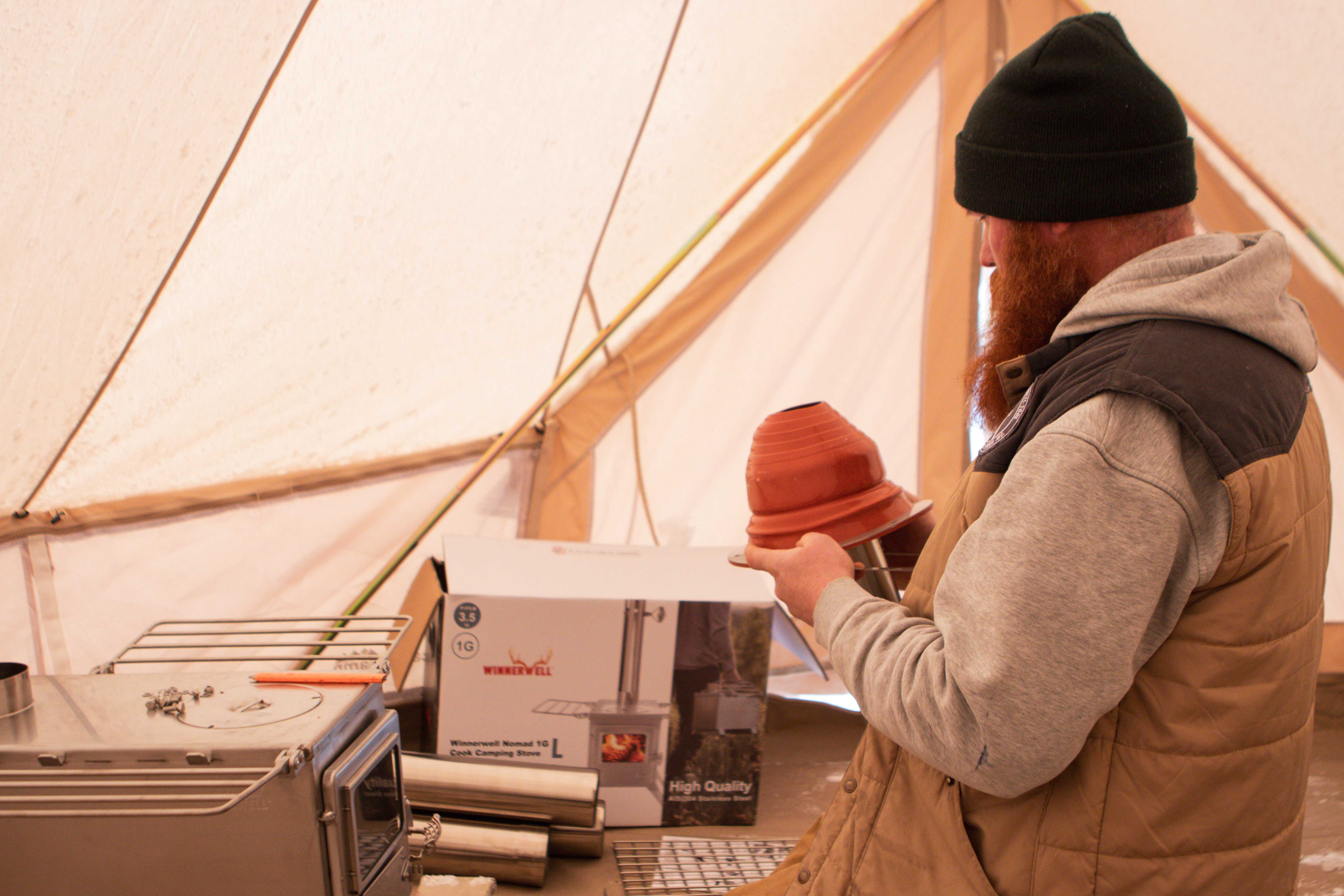 Man holding tent stove jack inside a sibley canvas tent Man holding tent stove jack inside a sibley canvas tent